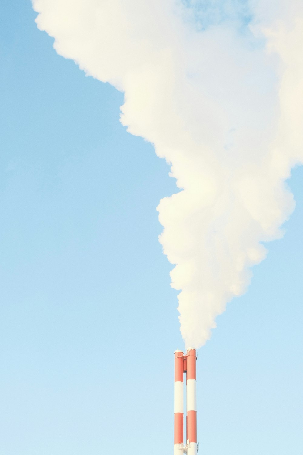 a smokestack emits from a pipe in front of a blue sky