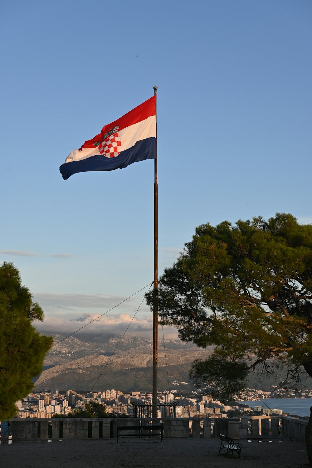 a flag flying in the wind with a city in the background