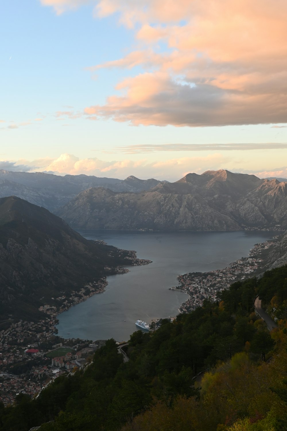 a view of a lake and mountains from the top of a hill