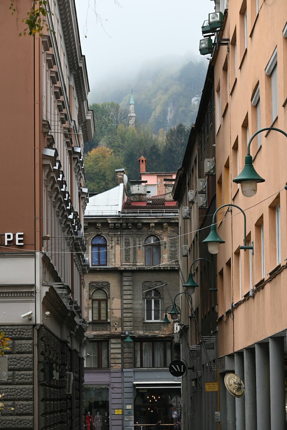 a narrow city street with a clock tower in the distance