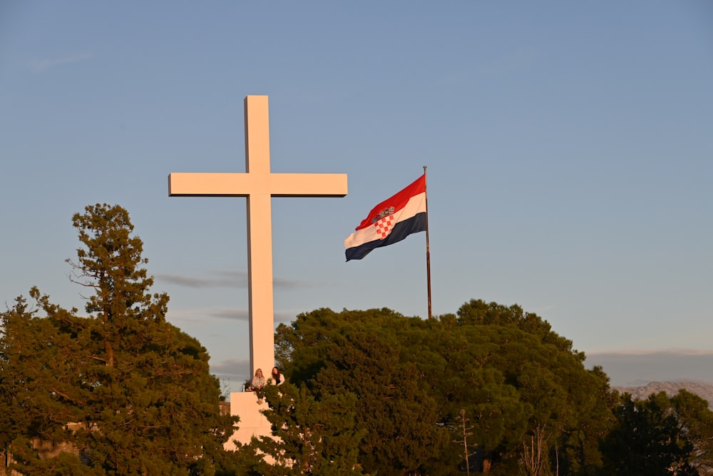 a cross and a flag flying in front of trees
