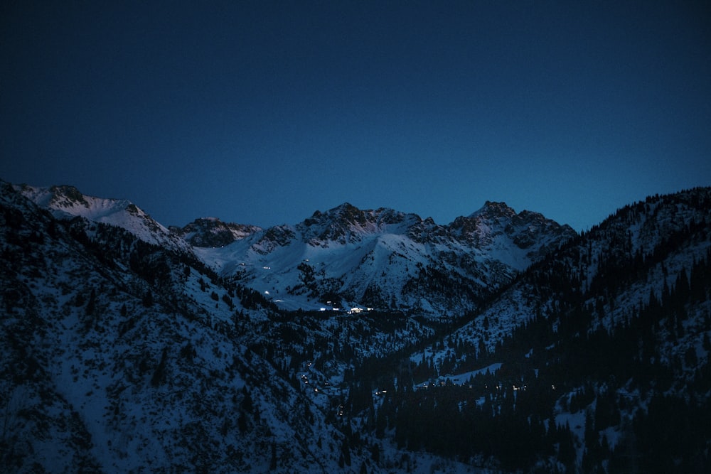 a view of a snowy mountain range at night