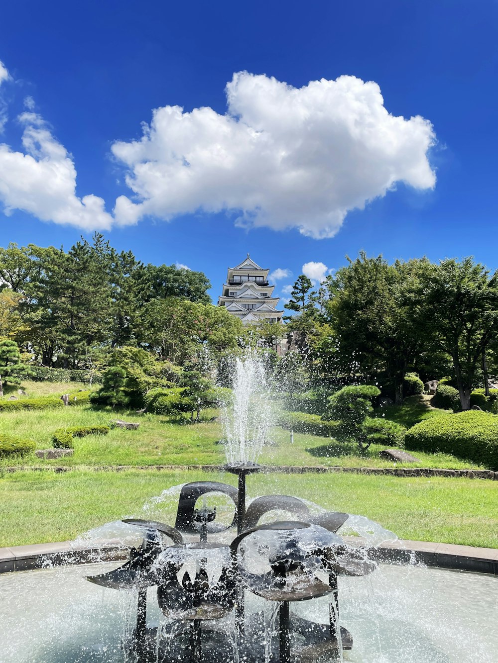 a fountain in a park with a castle in the background