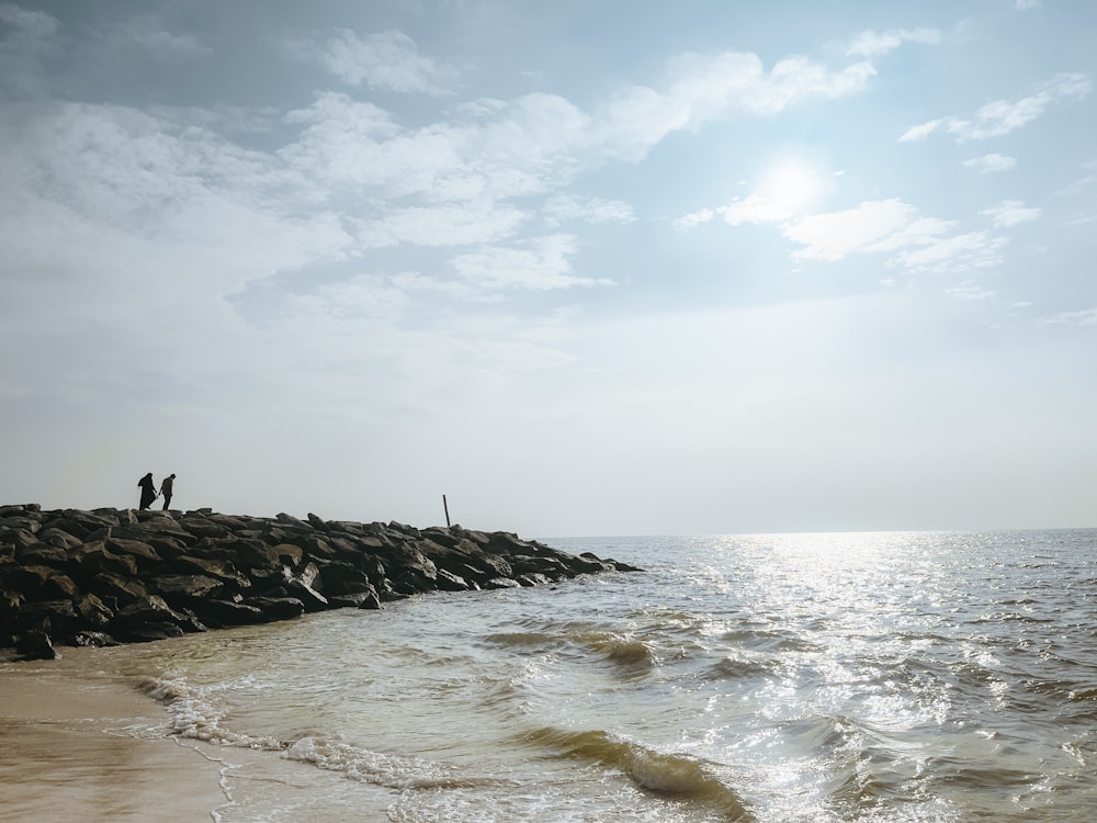 a couple of people standing on top of a beach next to the ocean