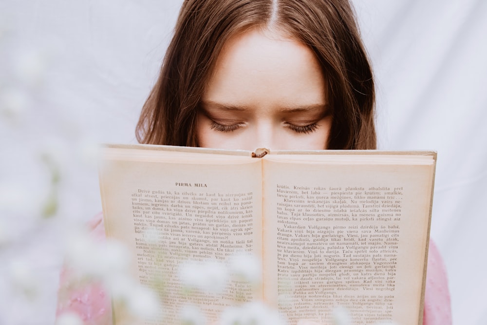 a woman reading a book with her eyes closed