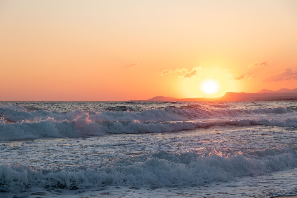 the sun is setting over the ocean waves