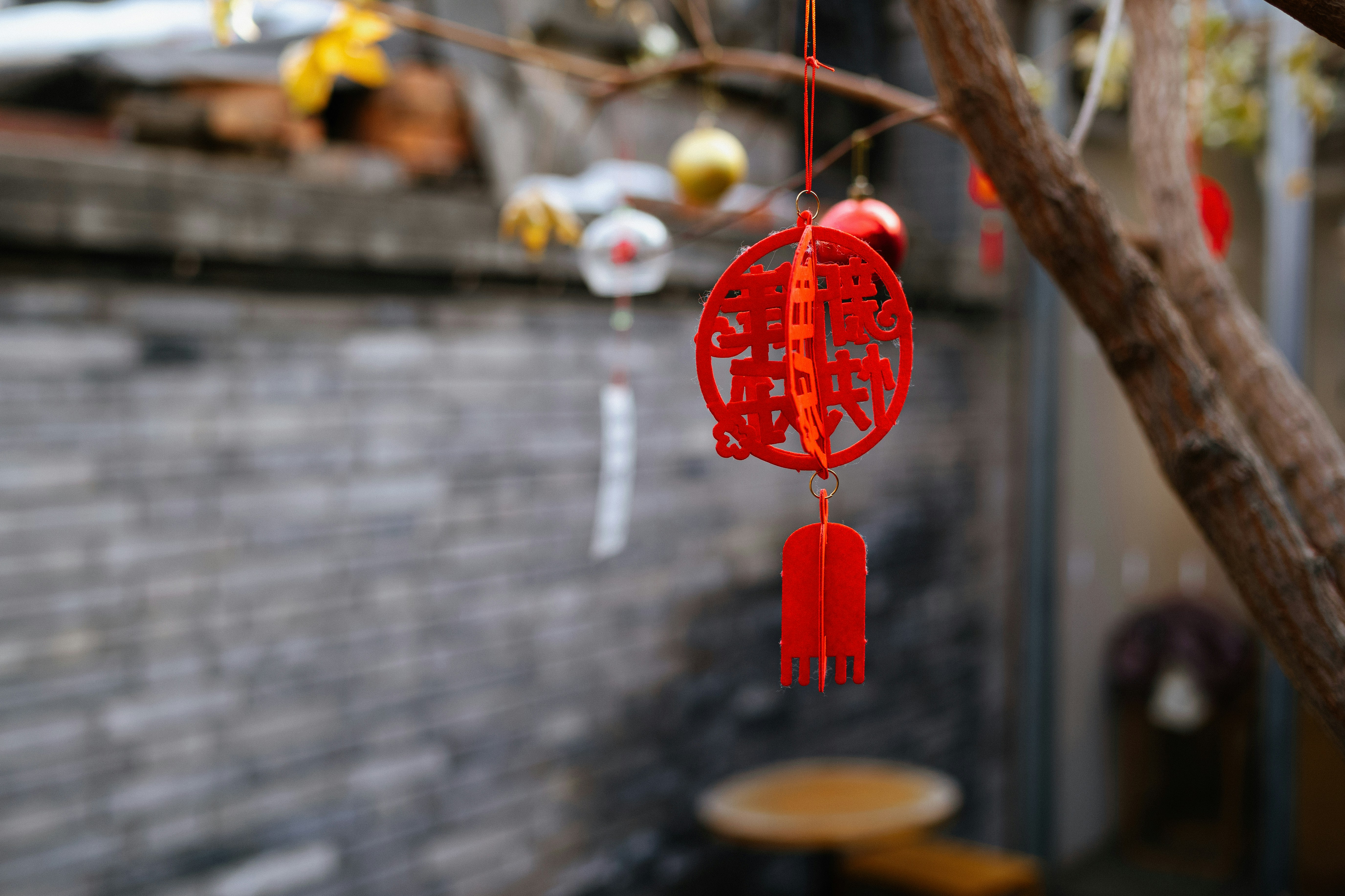 a red chinese style wind chime hanging from a tree
