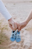 a close up of two people holding hands and baby shoes