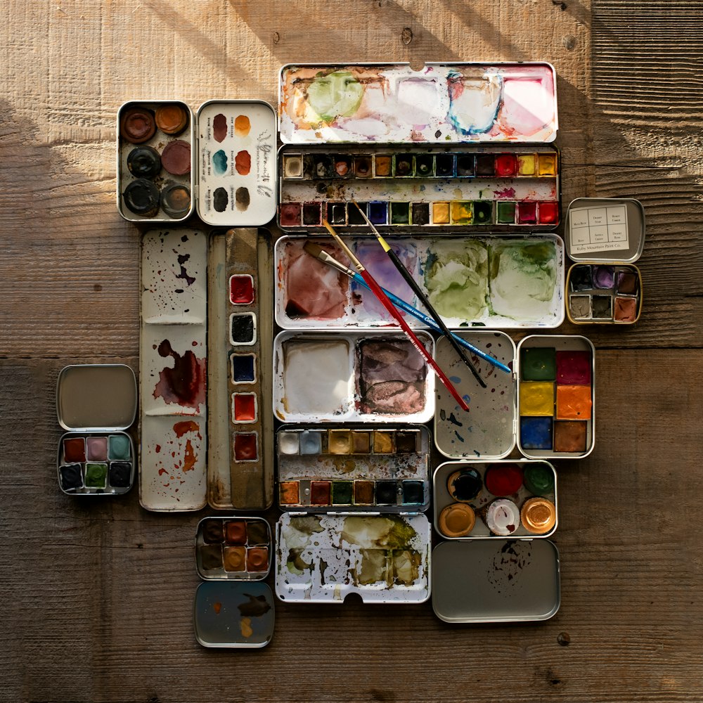 une table en bois surmontée de beaucoup de peinture et de pinceaux