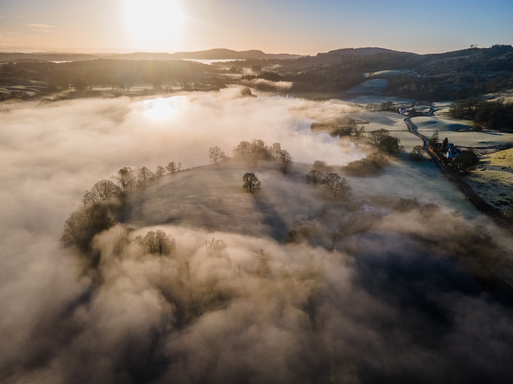 the sun is shining over a foggy valley