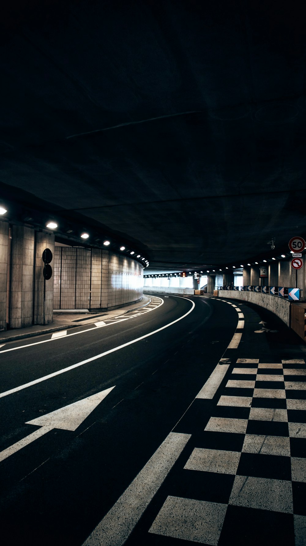 Un tunnel buio con pavimento a scacchi e luci