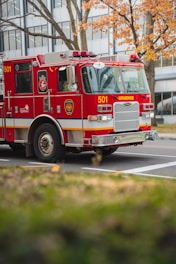 a red fire truck driving down a street next to a tall building