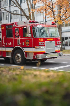 a red fire truck driving down a street next to a tall building