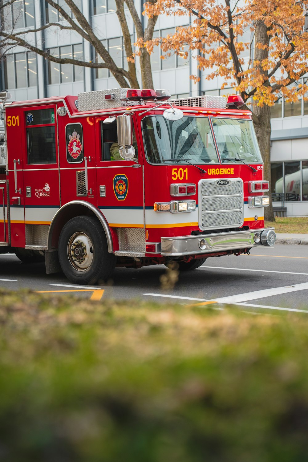 a red fire truck driving down a street next to a tall building