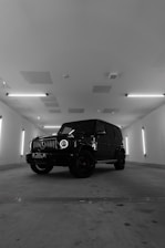 a black and white photo of a jeep in a parking garage
