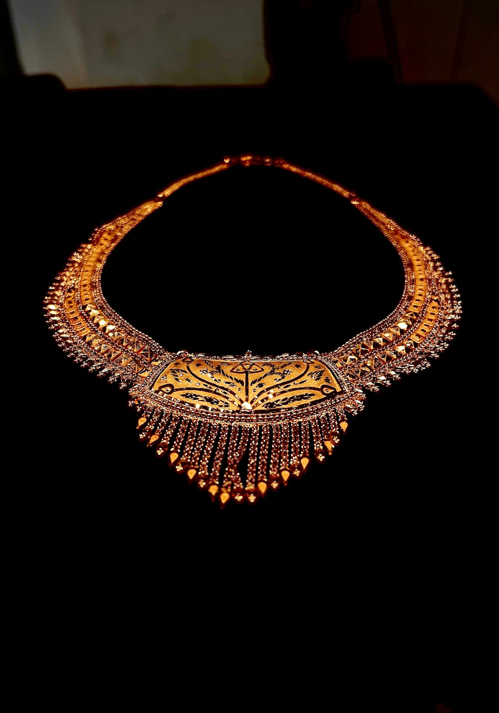 a gold necklace on display in a dark room