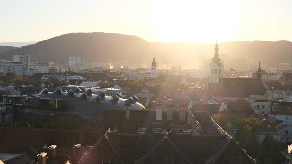 Die Sonne geht über einer Stadt mit Bergen im Hintergrund unter