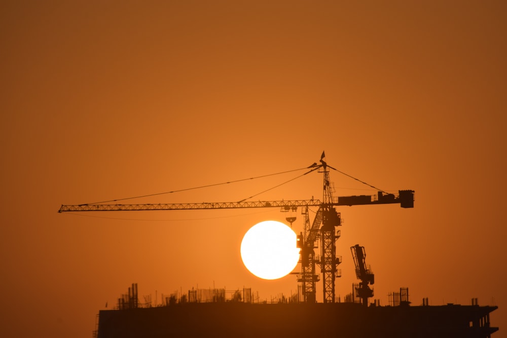the sun is setting behind a construction site