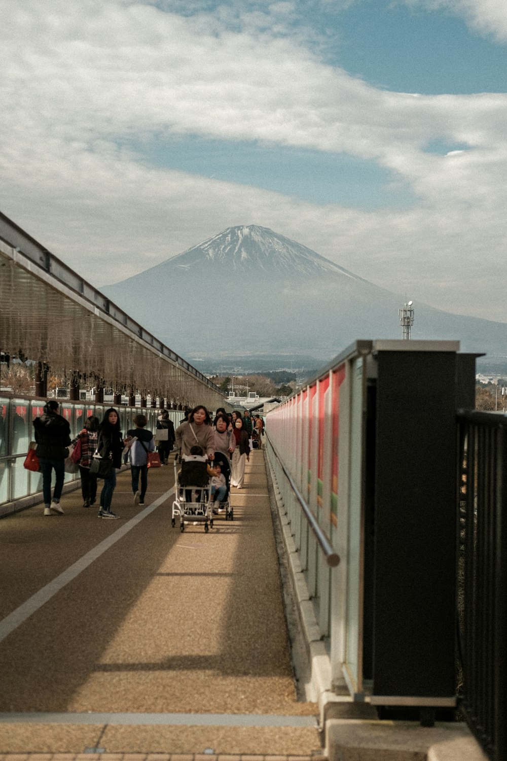 a group of people walking down a sidewalk next to a train