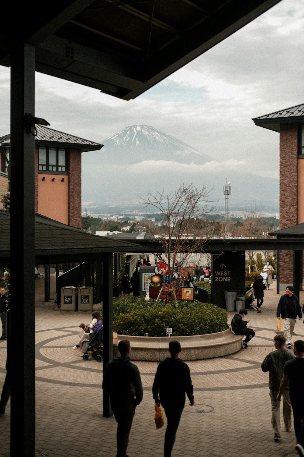 a group of people walking around a courtyard with a mountain in the background