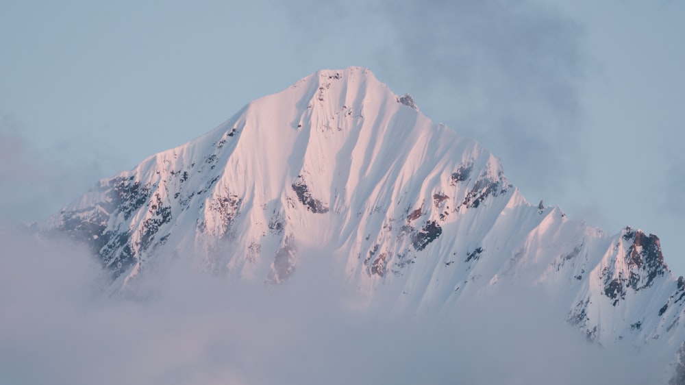 a snow covered mountain with clouds in the foreground