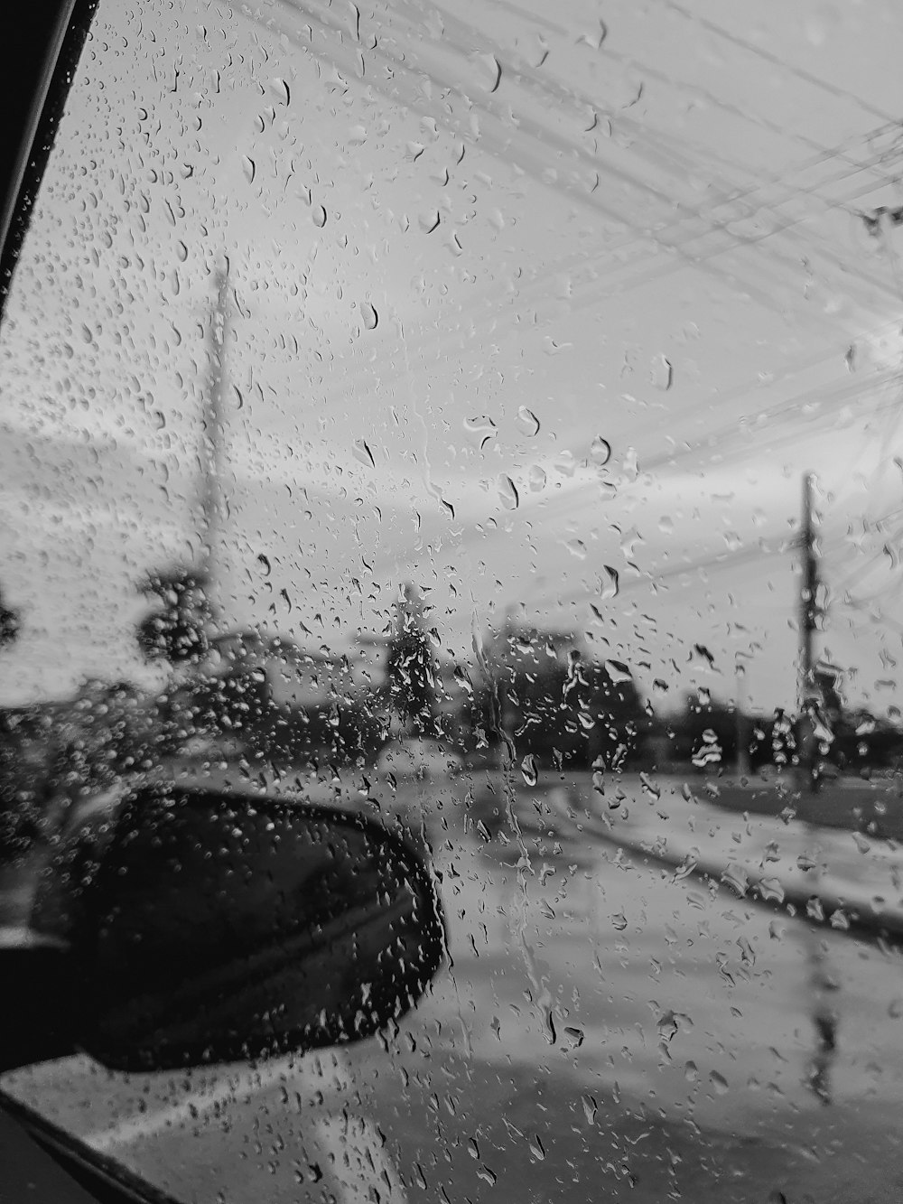 Una vista di una strada attraverso un parabrezza coperto di pioggia