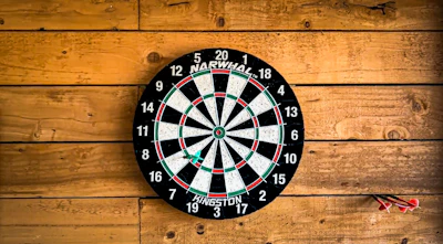 a dart hitting in the center of a dartboard on a wooden wall