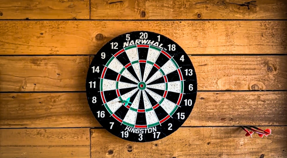 a dart hitting in the center of a dartboard on a wooden wall
