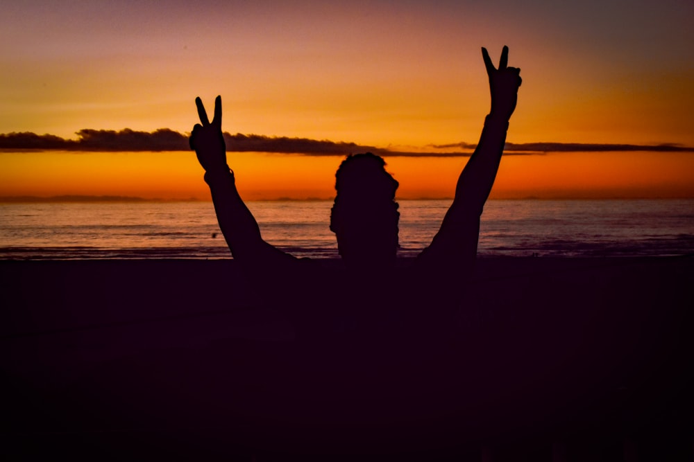 a person on a beach with their hands in the air