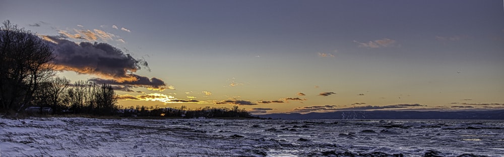 the sun is setting over the water at the beach