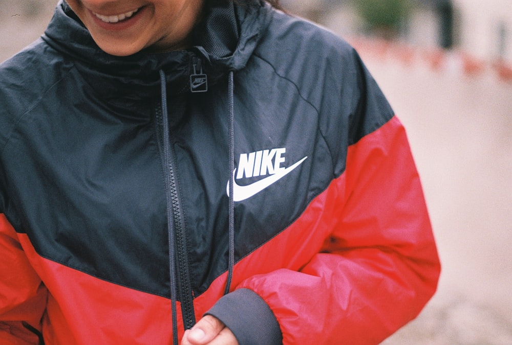 Eine Frau in einer schwarz-roten Jacke lächelt
