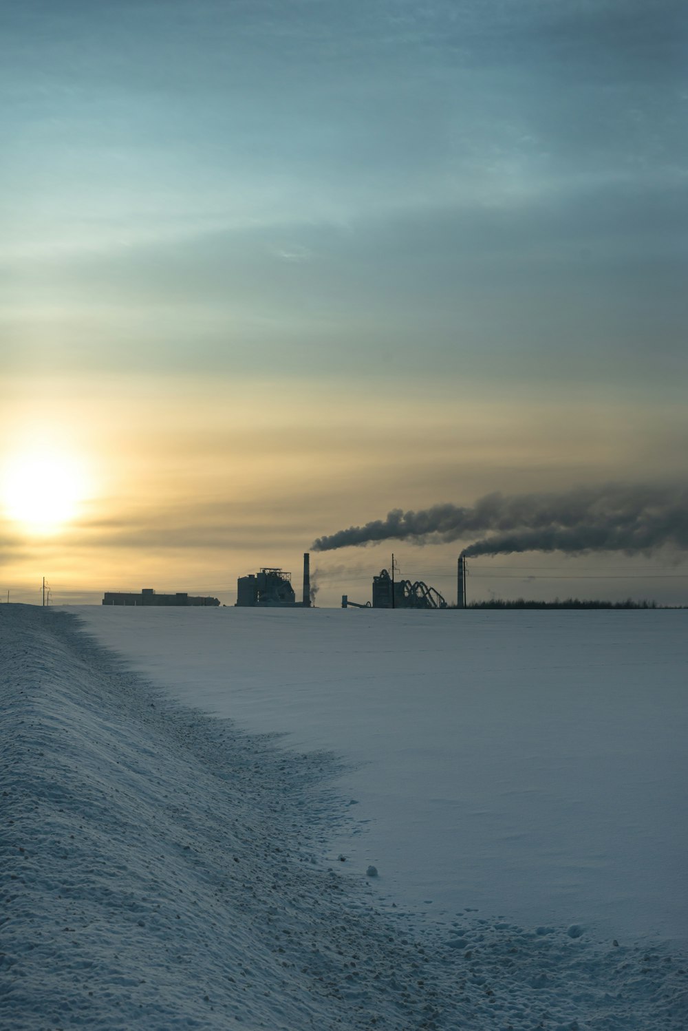 the sun is setting over a snow covered field