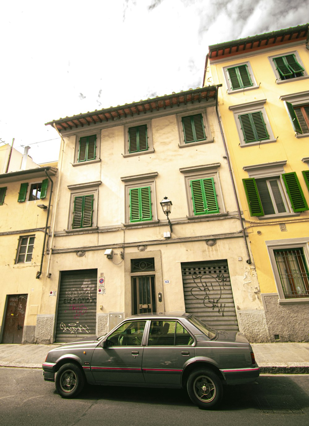 a car parked in front of a building with green shutters