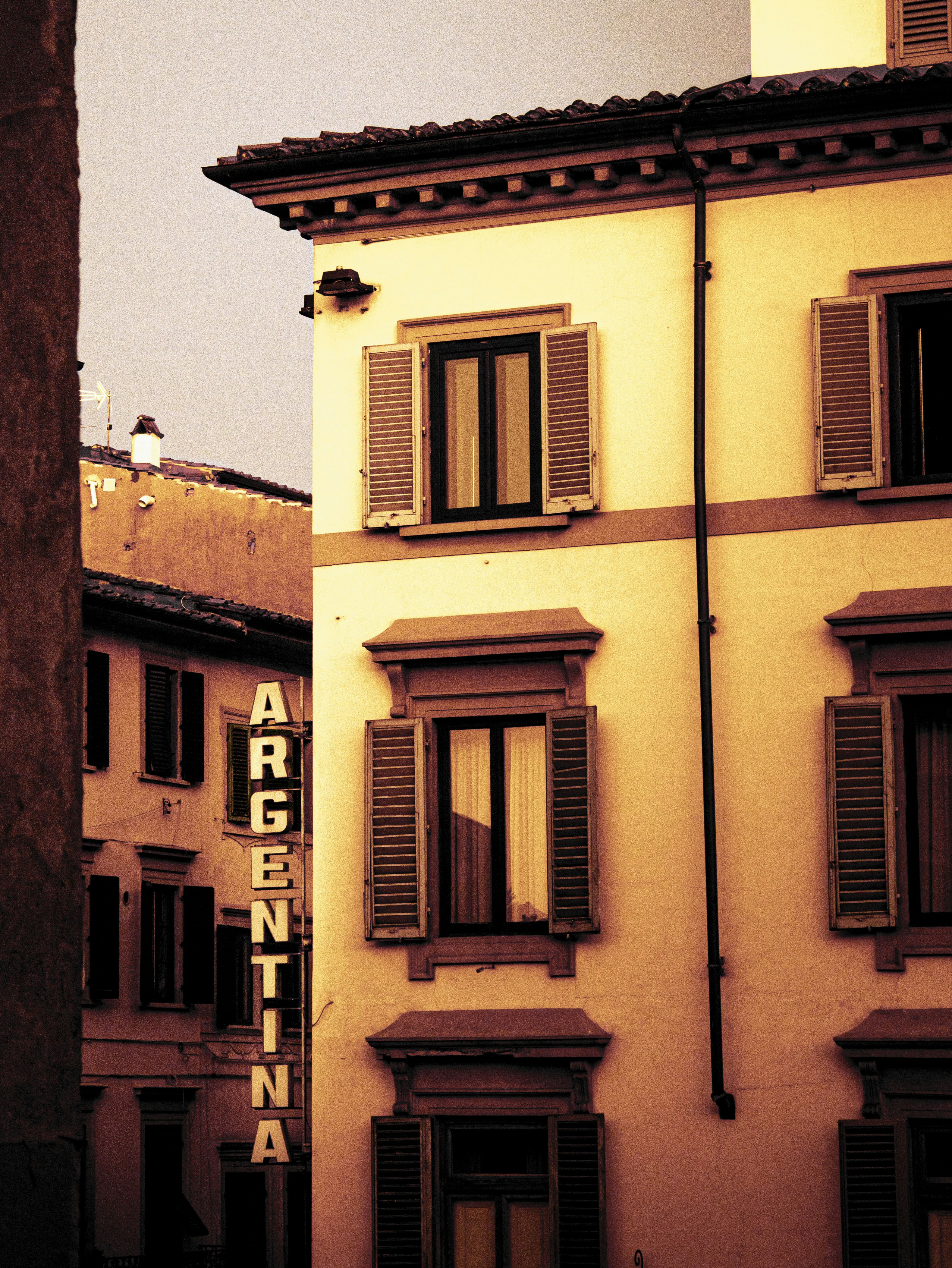 a tall building with windows and shutters on the side of it