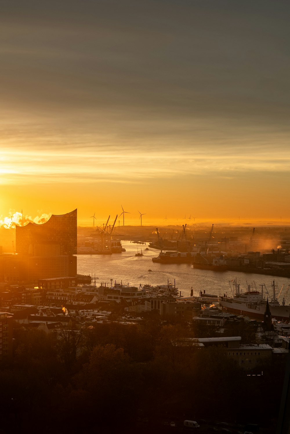 the sun is setting over a city and a body of water