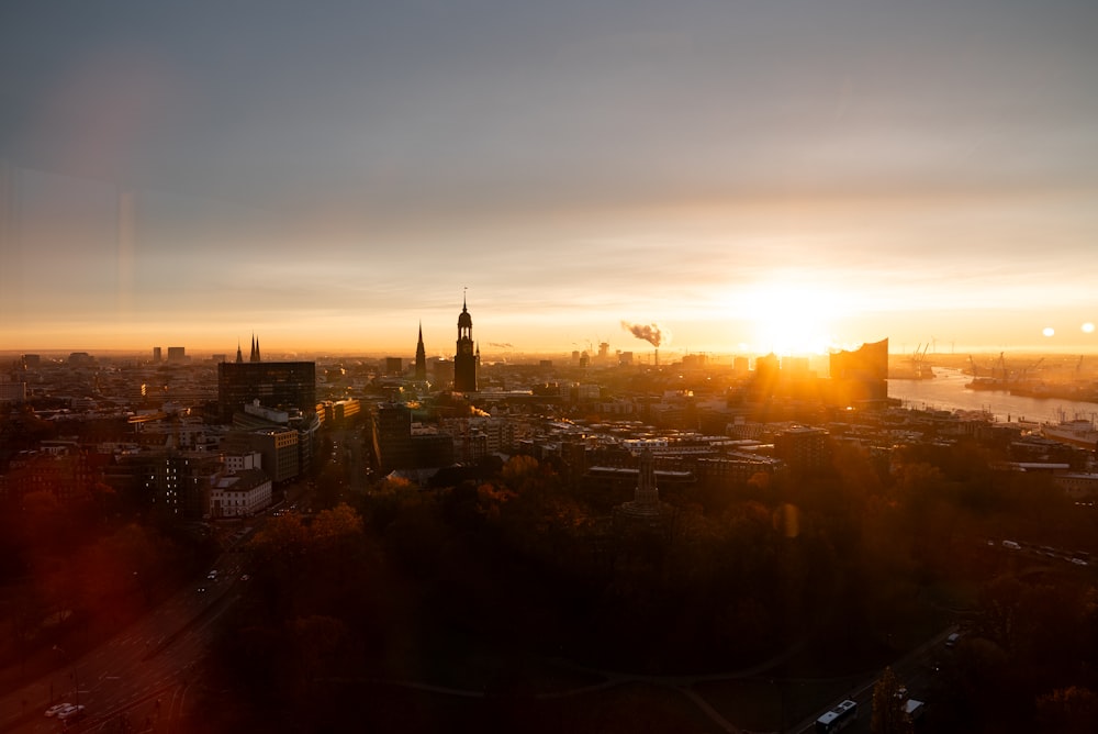 the sun is setting over a city with tall buildings