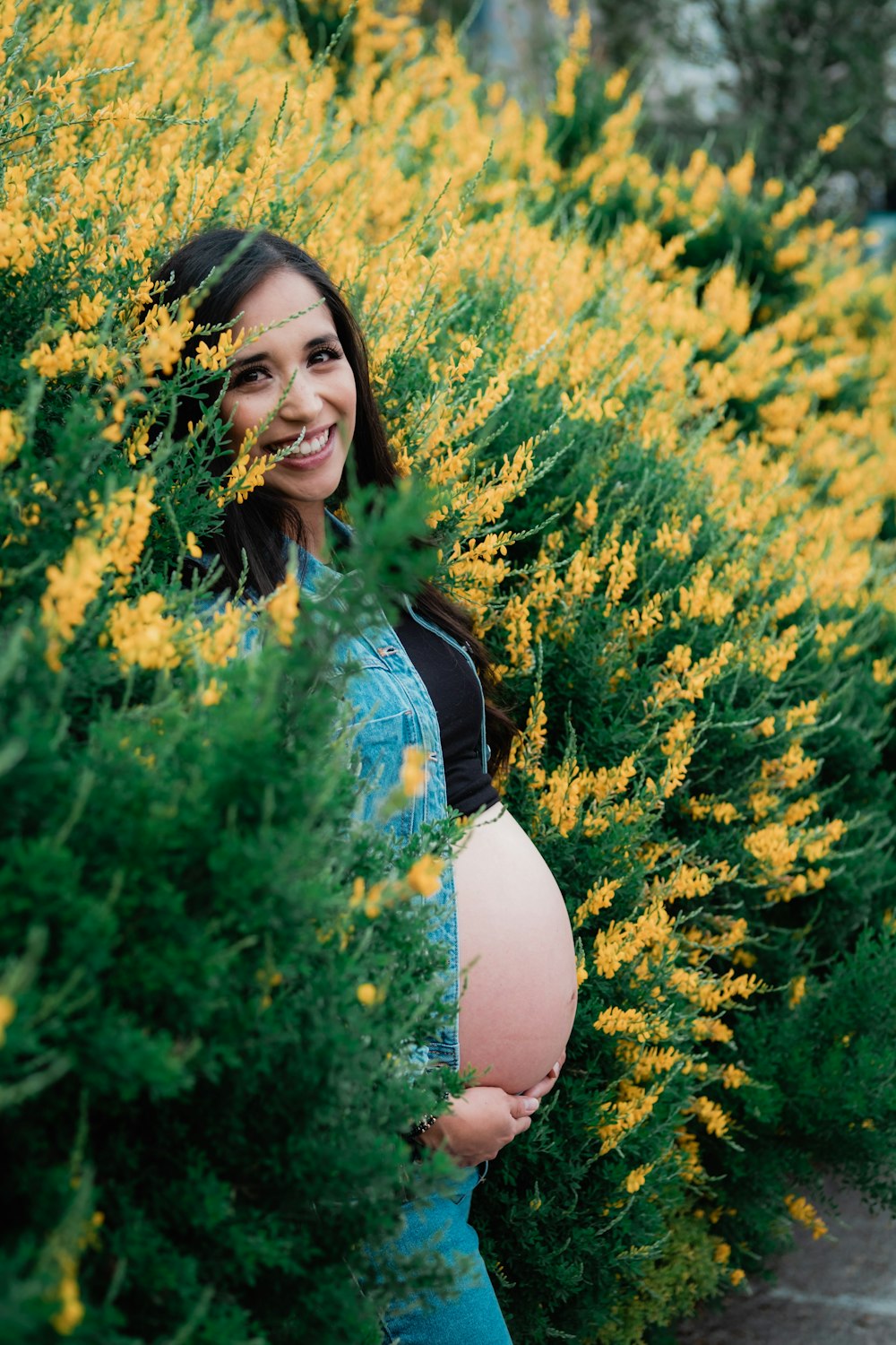 a pregnant woman standing in a field of yellow flowers