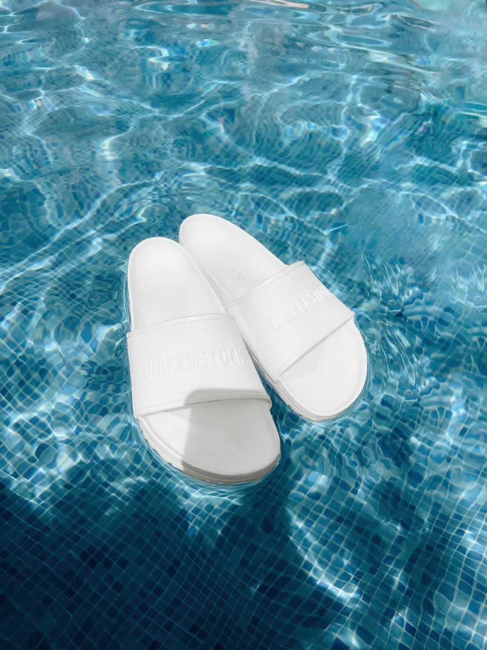 a pair of white slippers floating in a pool of water