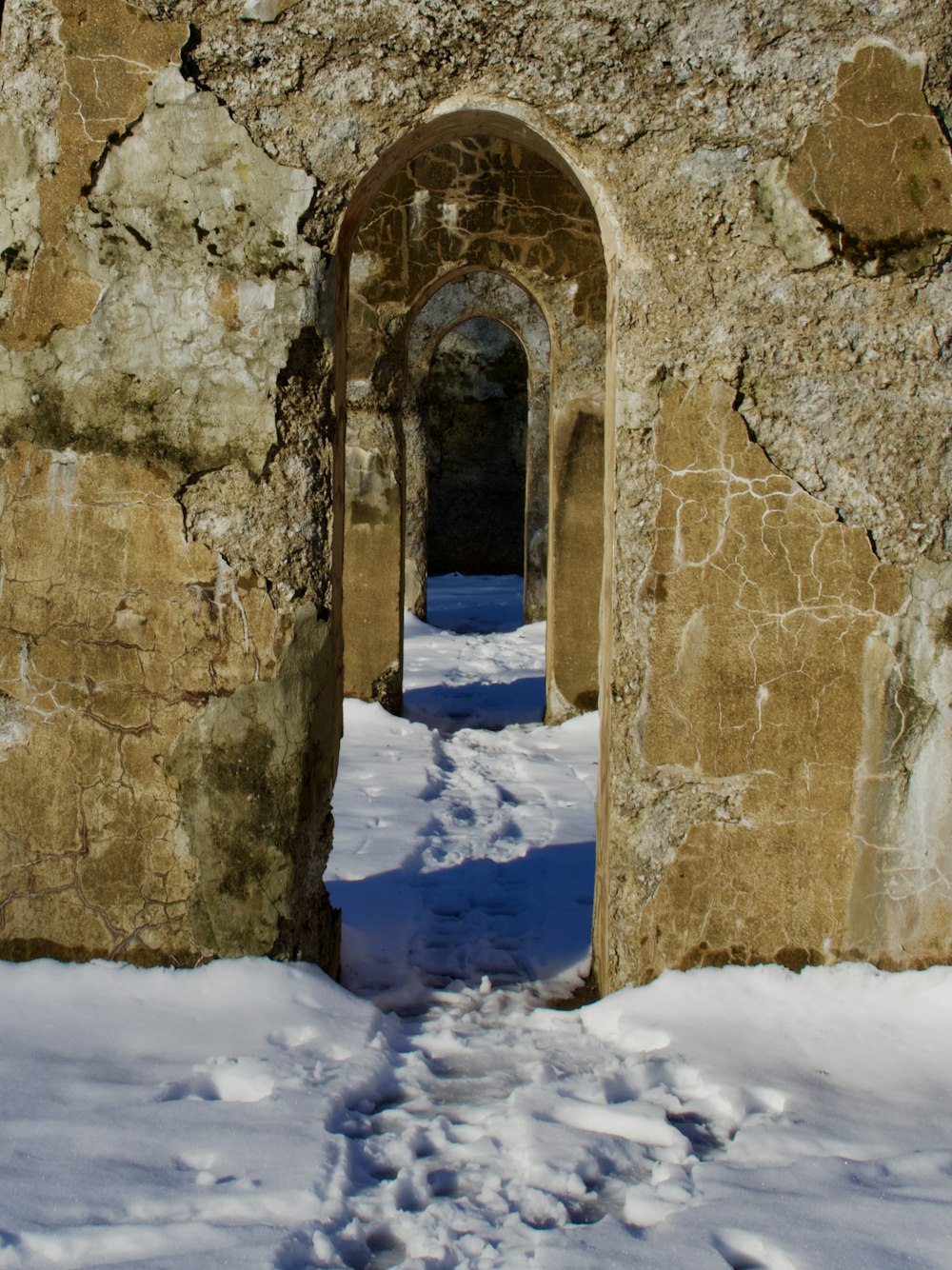 a stone wall with a doorway and snow on the ground