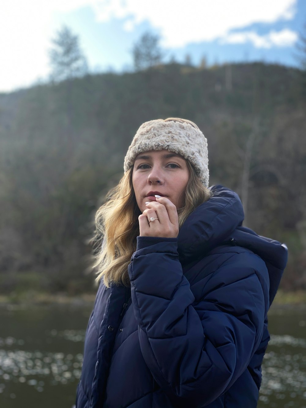 a woman in a blue jacket is standing by the water