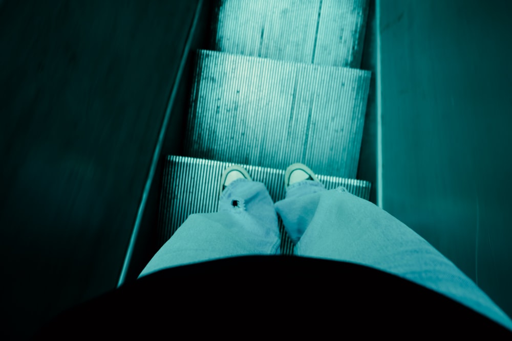 a person standing on an escalator with their feet up