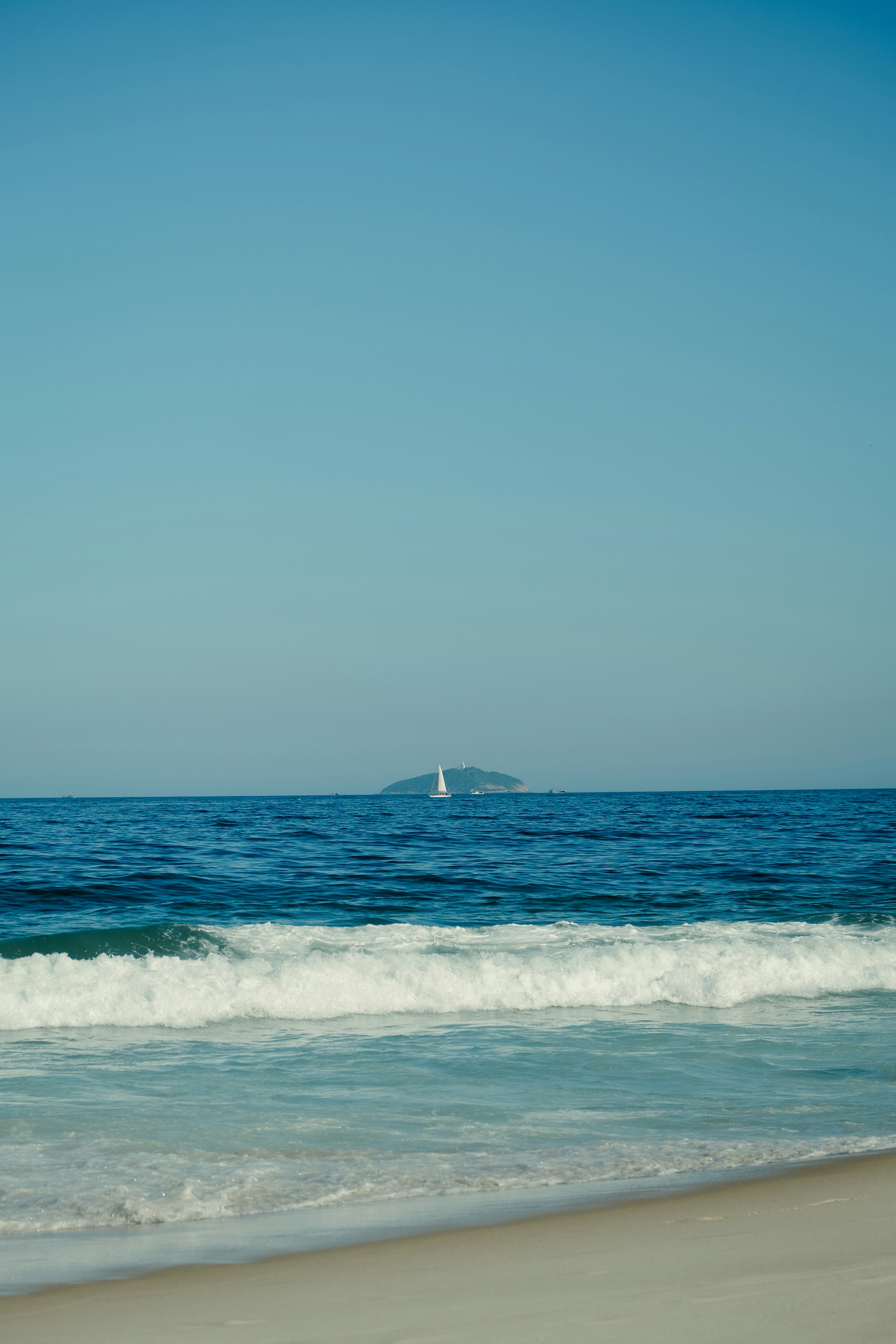 A sailboat is in the distance on the ocean photo – Free Beach Image on ...