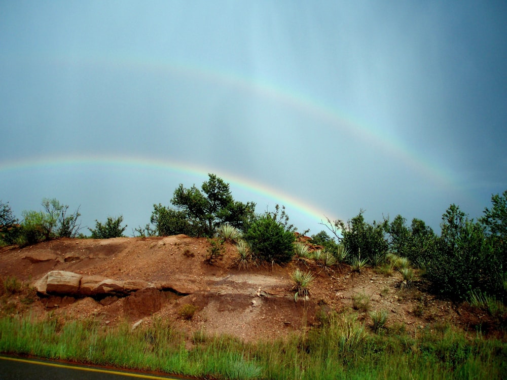 a double rainbow is seen over a dirt hill