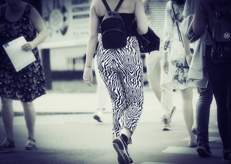 Stylish woman walking street with backpack
