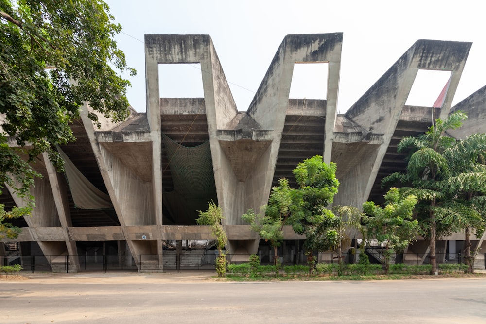 un grand bâtiment en béton avec des arbres devant