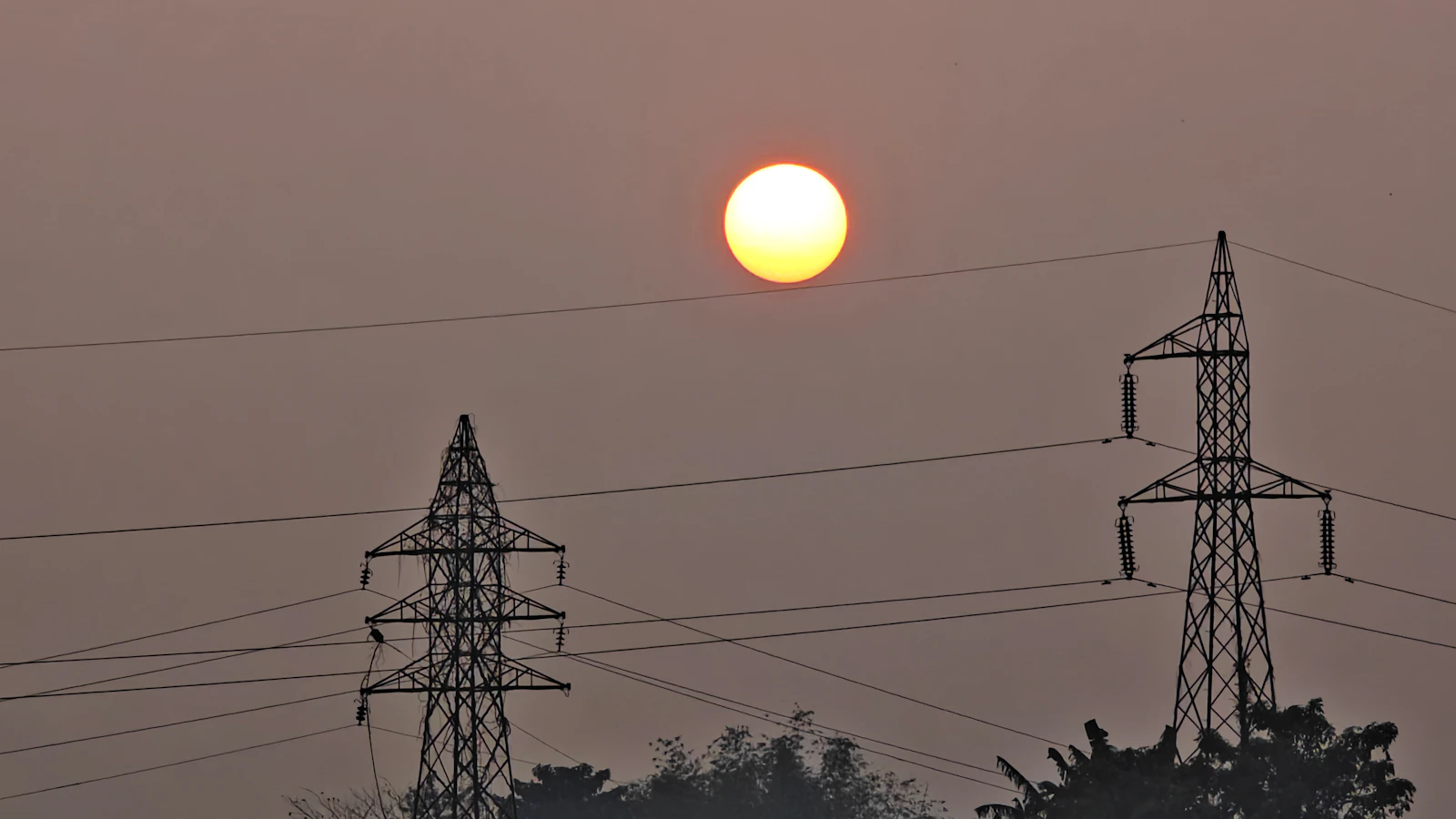 The sun setting behind high-voltage transmission towers