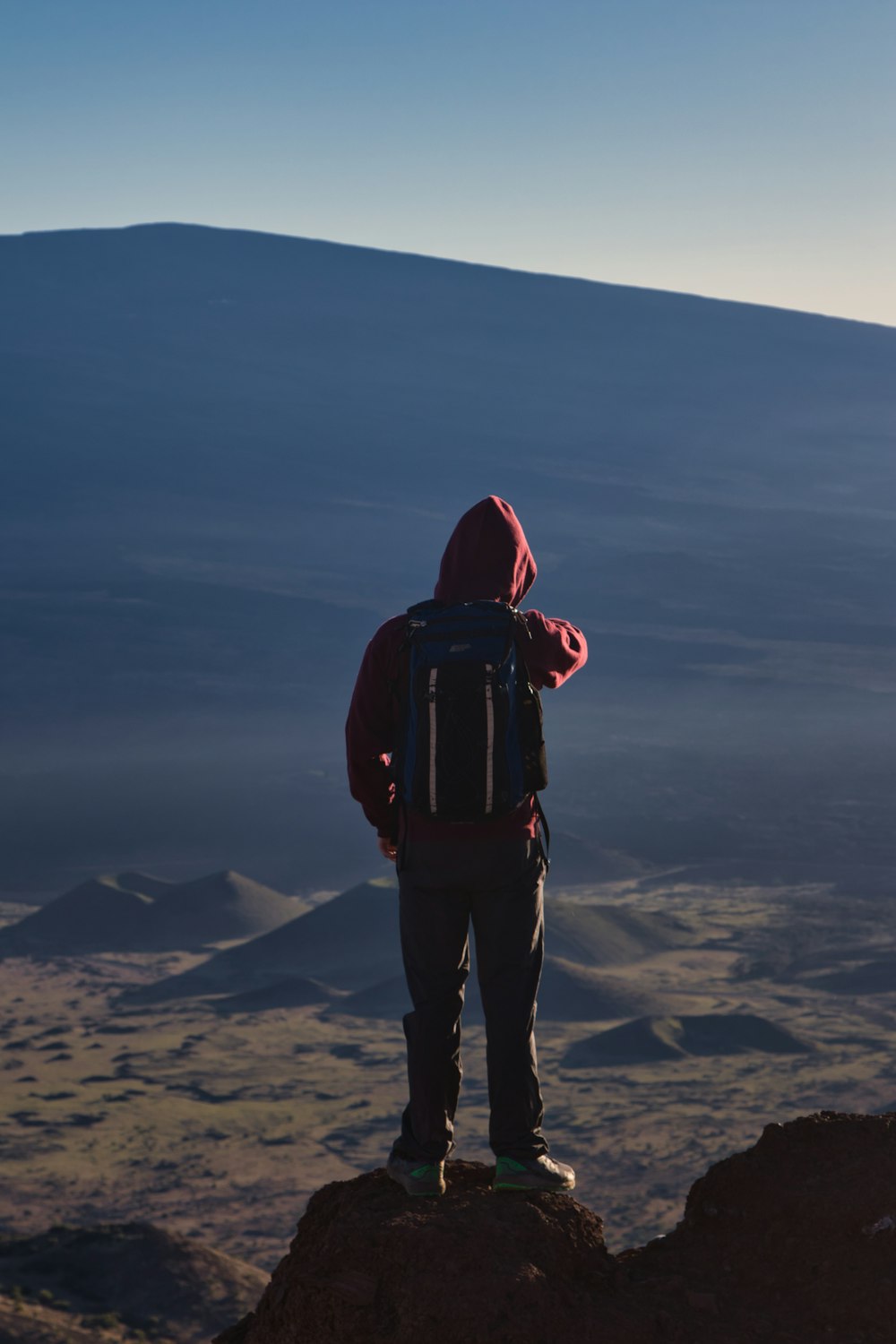 una persona parada en la cima de una montaña con una mochila