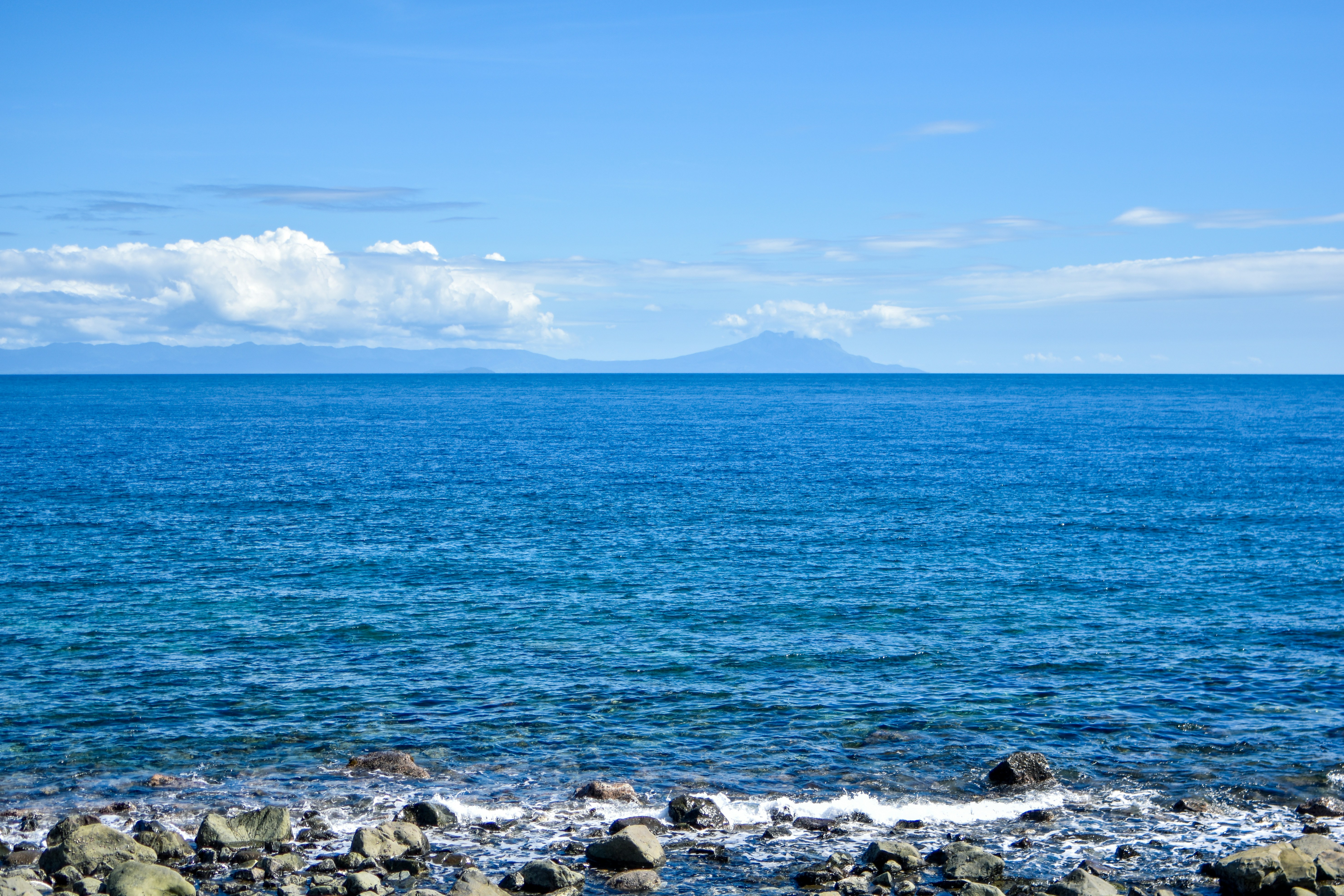 a large body of water sitting next to a rocky shore, 