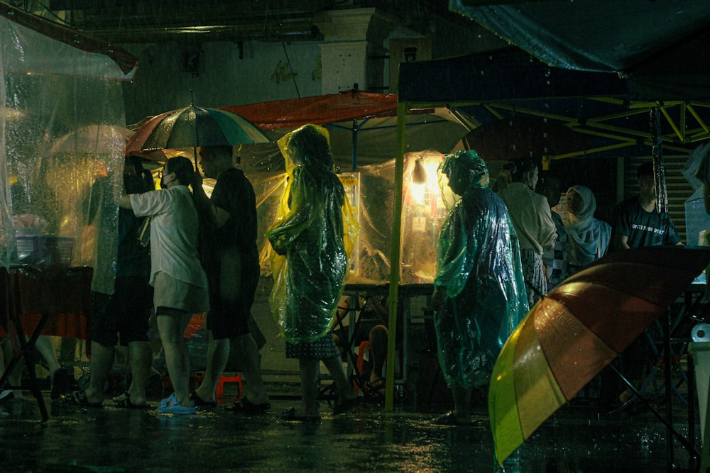 un gruppo di persone in piedi sotto gli ombrelli sotto la pioggia