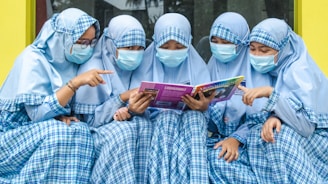 a group of women in blue dresses reading a book
